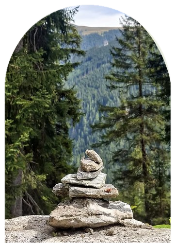 Aufeinandergeschichtete Steine vor einem Bergwald