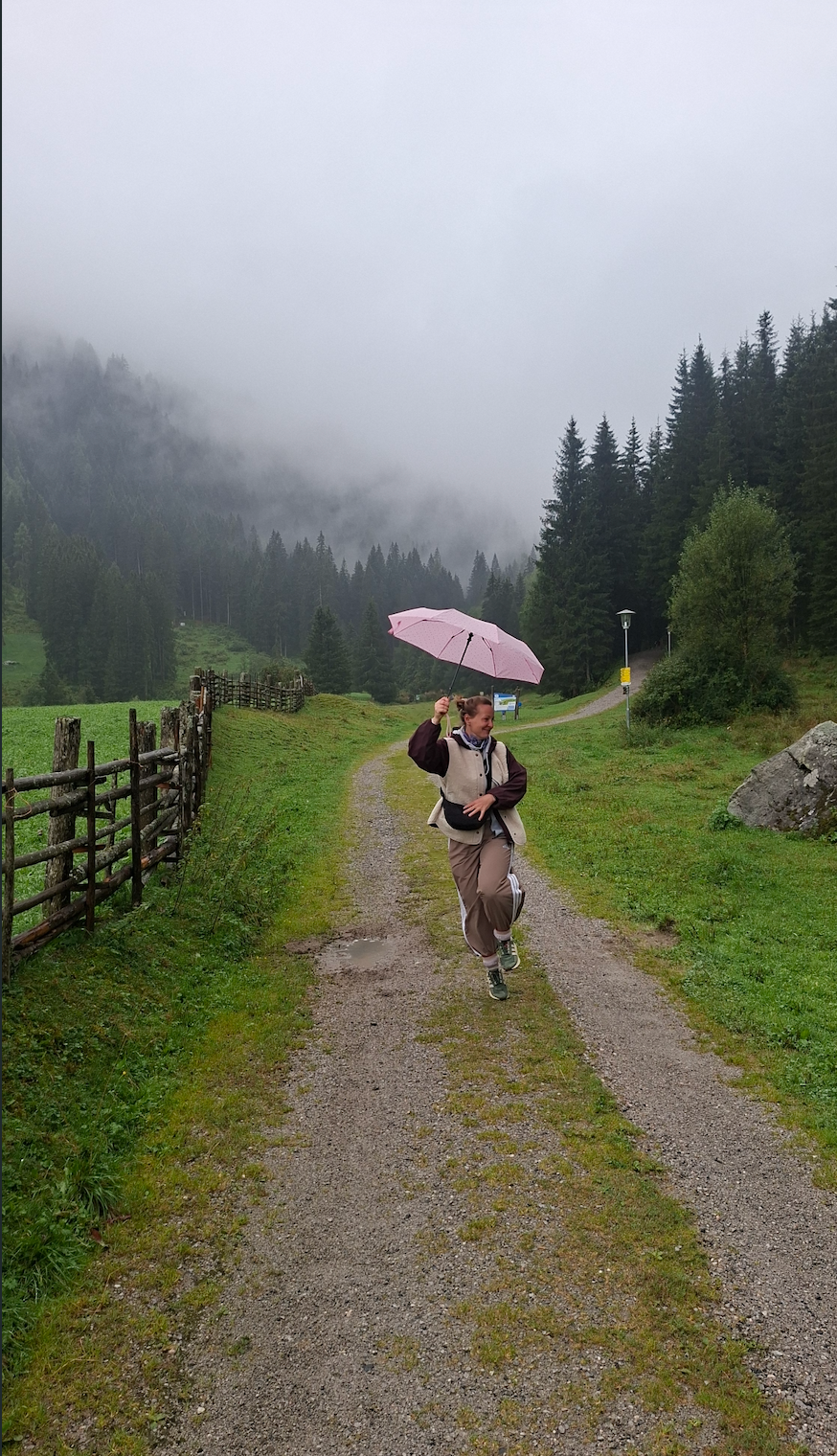 Sophie mit rosa Regenschirm auf einem Waldweg im Nebel