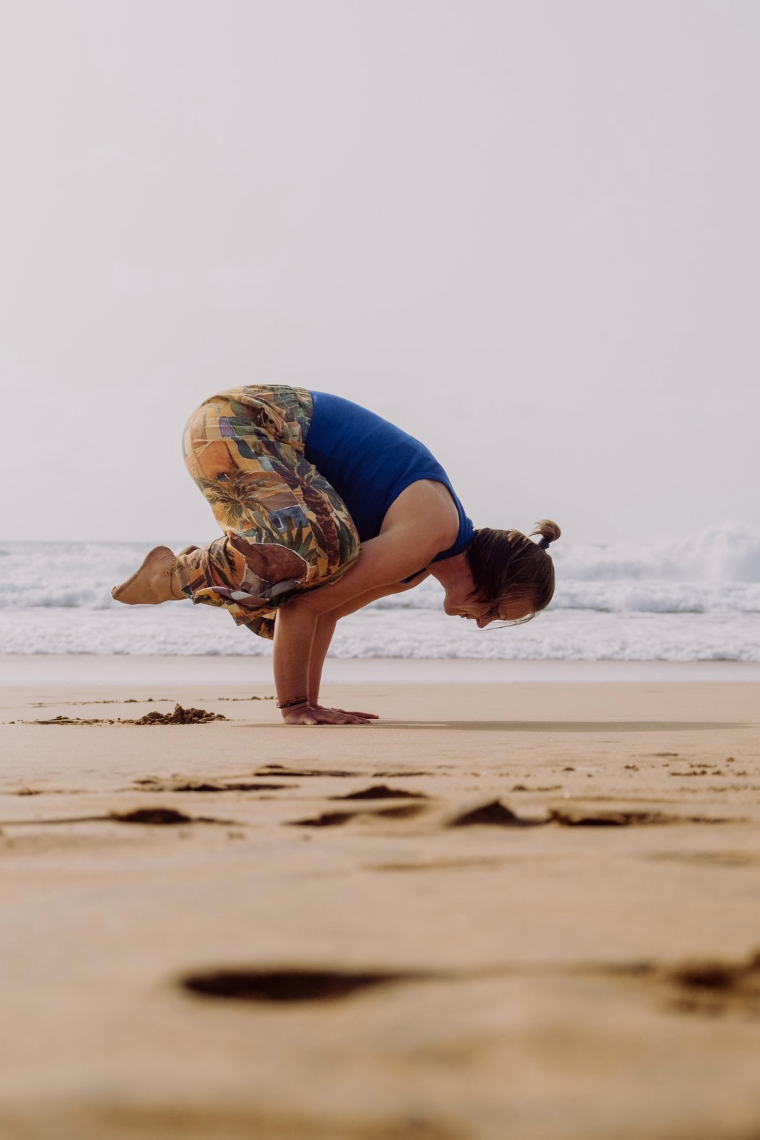 Sophie in einer Yoga-Armbalance am Strand